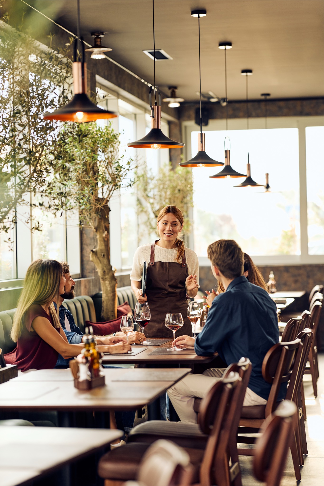 Servicemitarbeiterin berät Gäste an einem Tisch im Bistro
