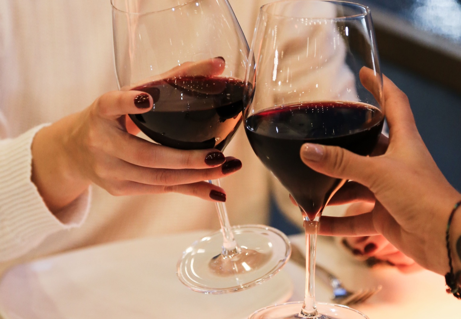 Zwei Gäste stossen mit Rotwein an